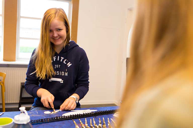 Design med samarbejde og inspiration Pige arbejder med pensel og guldmaling